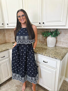 Entro navy blue sleeveless midi dress with white starburst pattern and eyelet trim. Woman wearing glasses stands in kitchen.