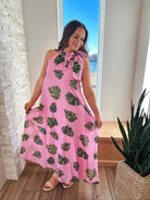 Pink maxi dress with a tropical palm leaf print and tie neck detail.