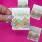 Spring floral stud earrings with pastel translucent petals in pink, blue, and green, centered with yellow and pink beads.