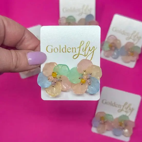 Spring floral stud earrings with pastel translucent petals in pink, blue, and green, centered with yellow and pink beads.