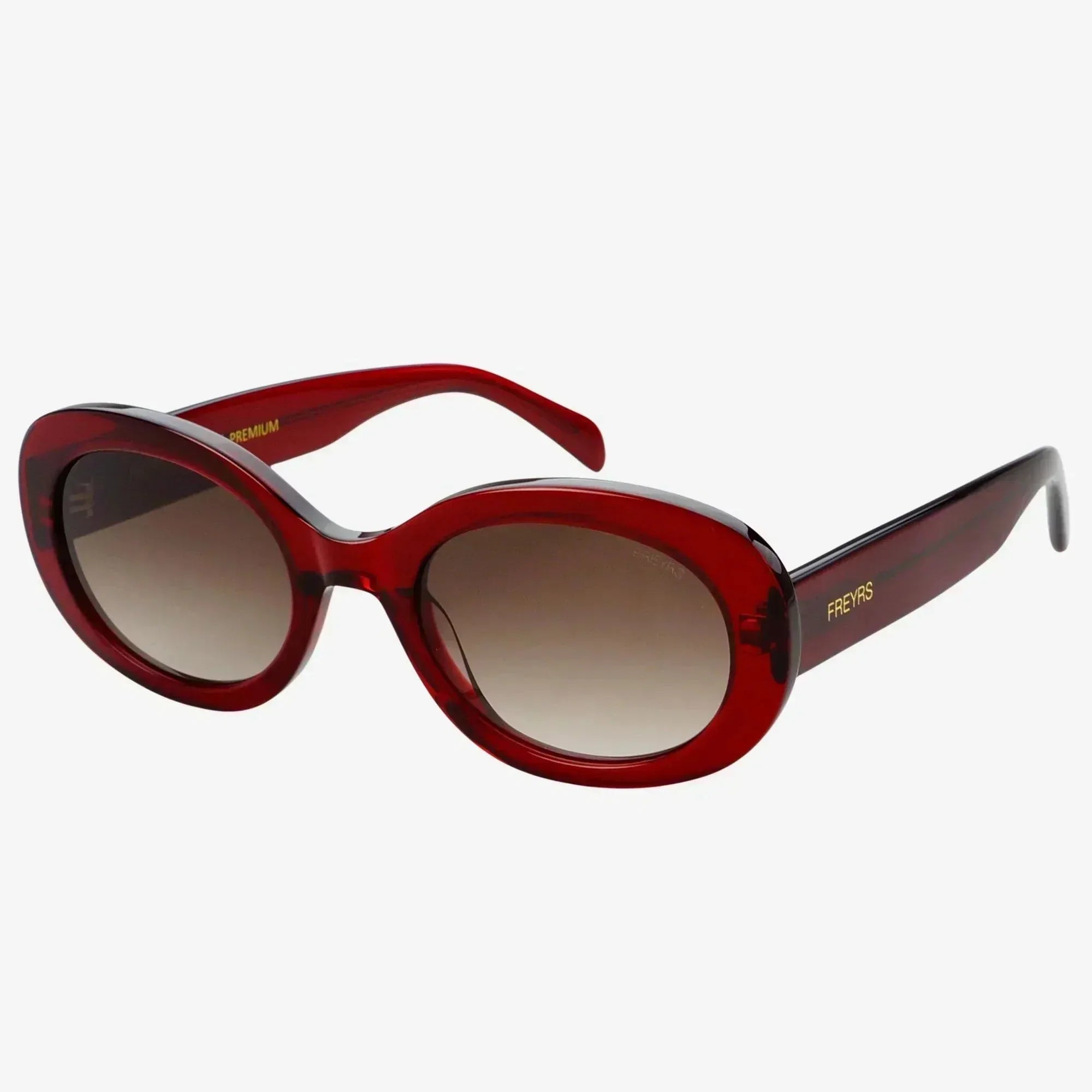 Freyrs Aria women's glossy red acetate oval sunglasses with gradient brown lenses and gold "FREYRS" logo on the arm.