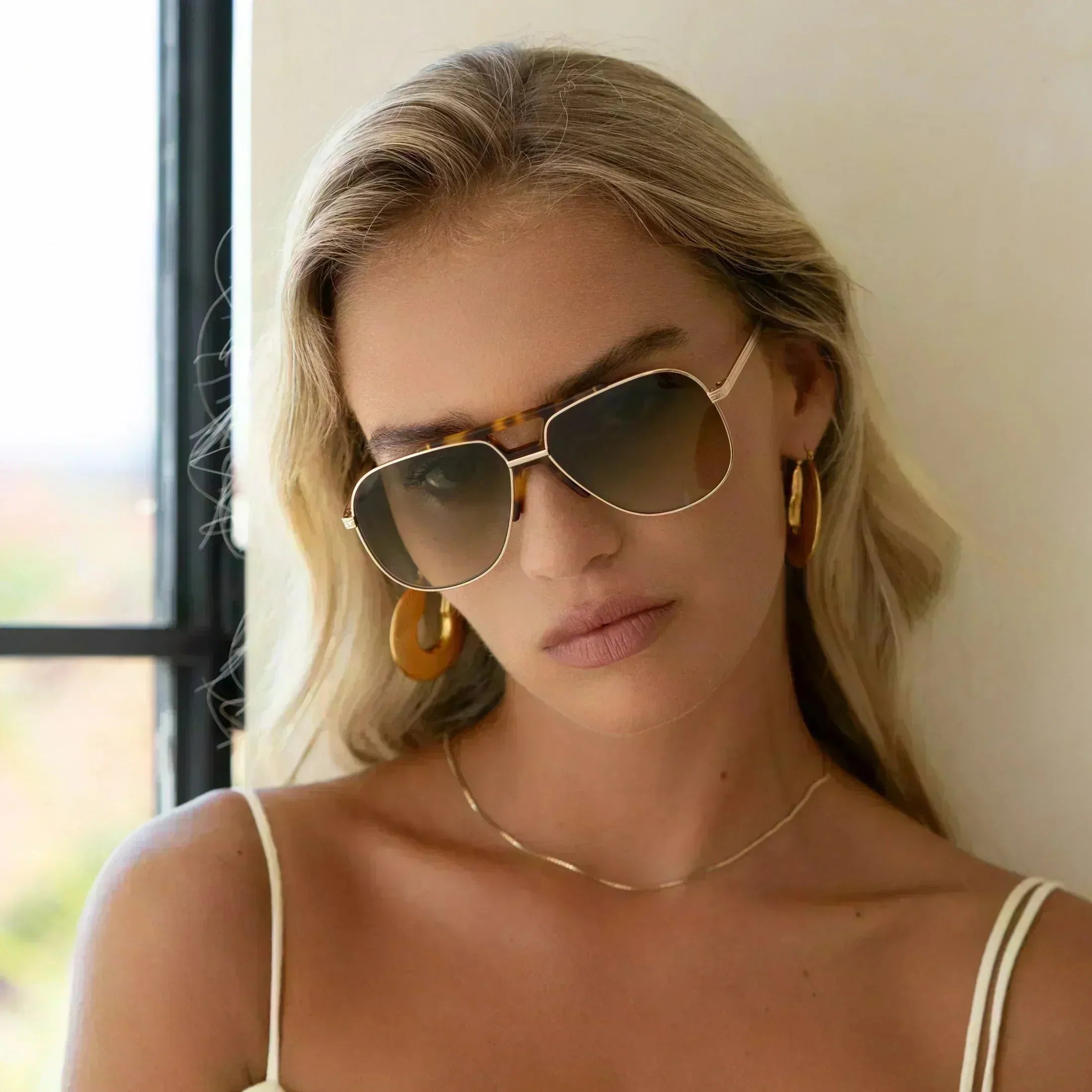 Close-up of a woman wearing Freyrs Logan aviator sunglasses with gold frames and tortoise shell accents.
