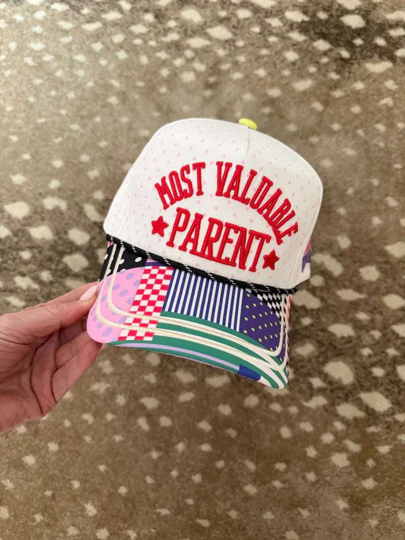 White snapback hat with pink polka dots and red embroidered text "MOST VALUABLE PARENT" with patchwork brim.