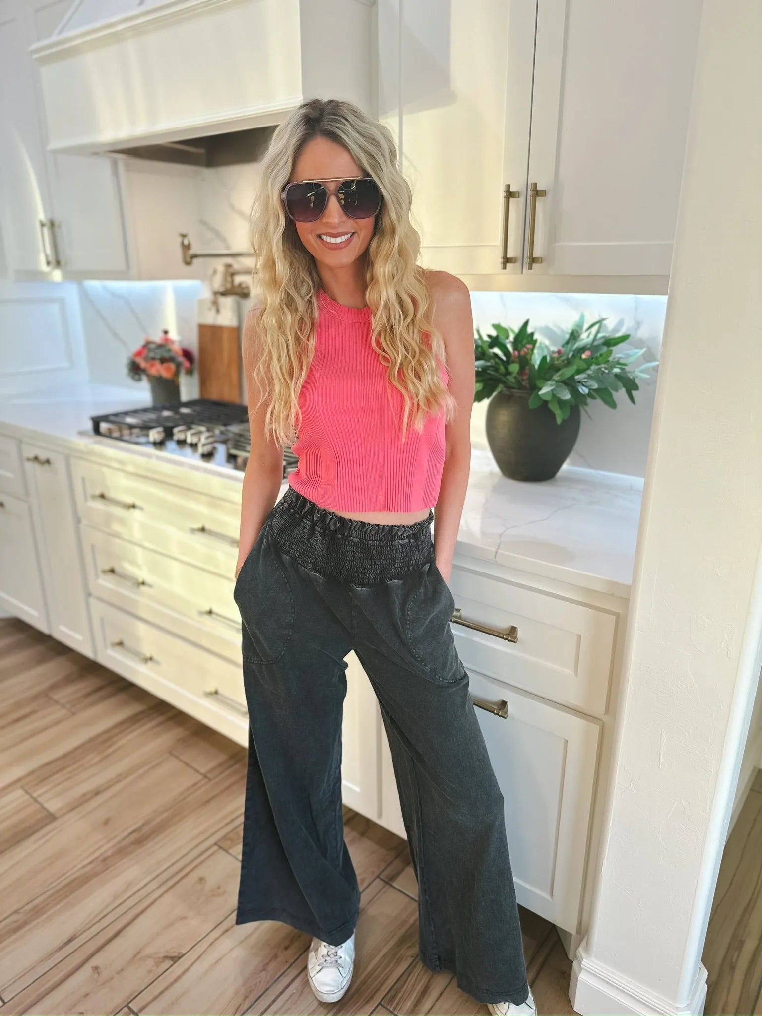 Woman wearing HyFVE black wash elastic waist wide leg trousers and a pink ribbed crop top, with sunglasses on.