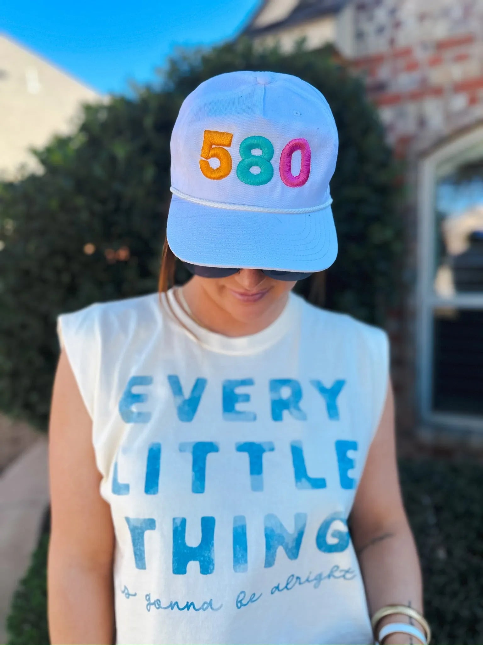 White Legacy Skully baseball cap with embroidered "580" in orange, teal, and pink. Features a rope bill and a person