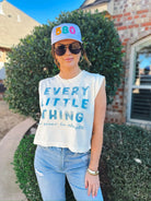 White baseball cap with embroidered colorful '580' on the front. Worn by a woman in a cream graphic t-shirt and jeans.