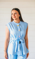 Light blue matching pant suit set for women. Sleeveless top with statement flower buttons in yellow, clear, and pink