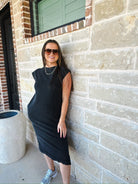 Model wearing a mineral wash oversized cotton midi dress in black with shoulder pads, sunglasses, silver necklace, and