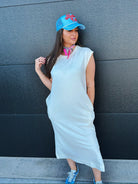 Oversized mineral wash white cotton midi dress with pockets, worn with a blue trucker hat and sneakers.