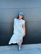 Mineral wash oversized cotton midi dress in off-white, styled with blue sneakers and a blue baseball cap reading "Batter Up!
