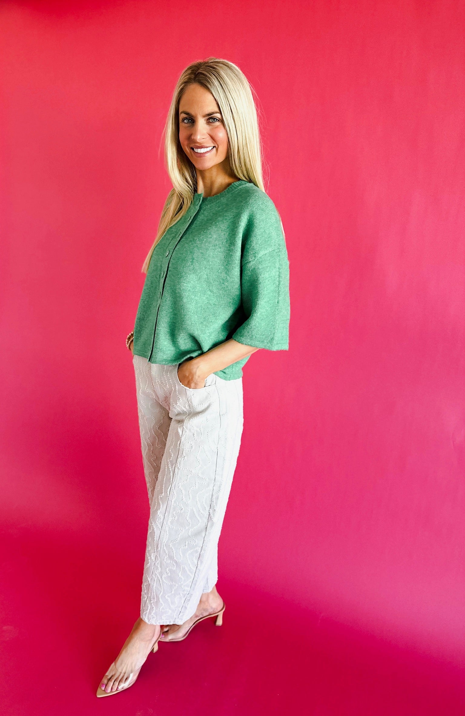 Model wearing Peach Love frayed ecru twill denim barrel pants and a green top against a bright pink background.
