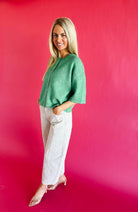 Model wearing Peach Love frayed ecru twill denim barrel pants and a green top against a bright pink background.
