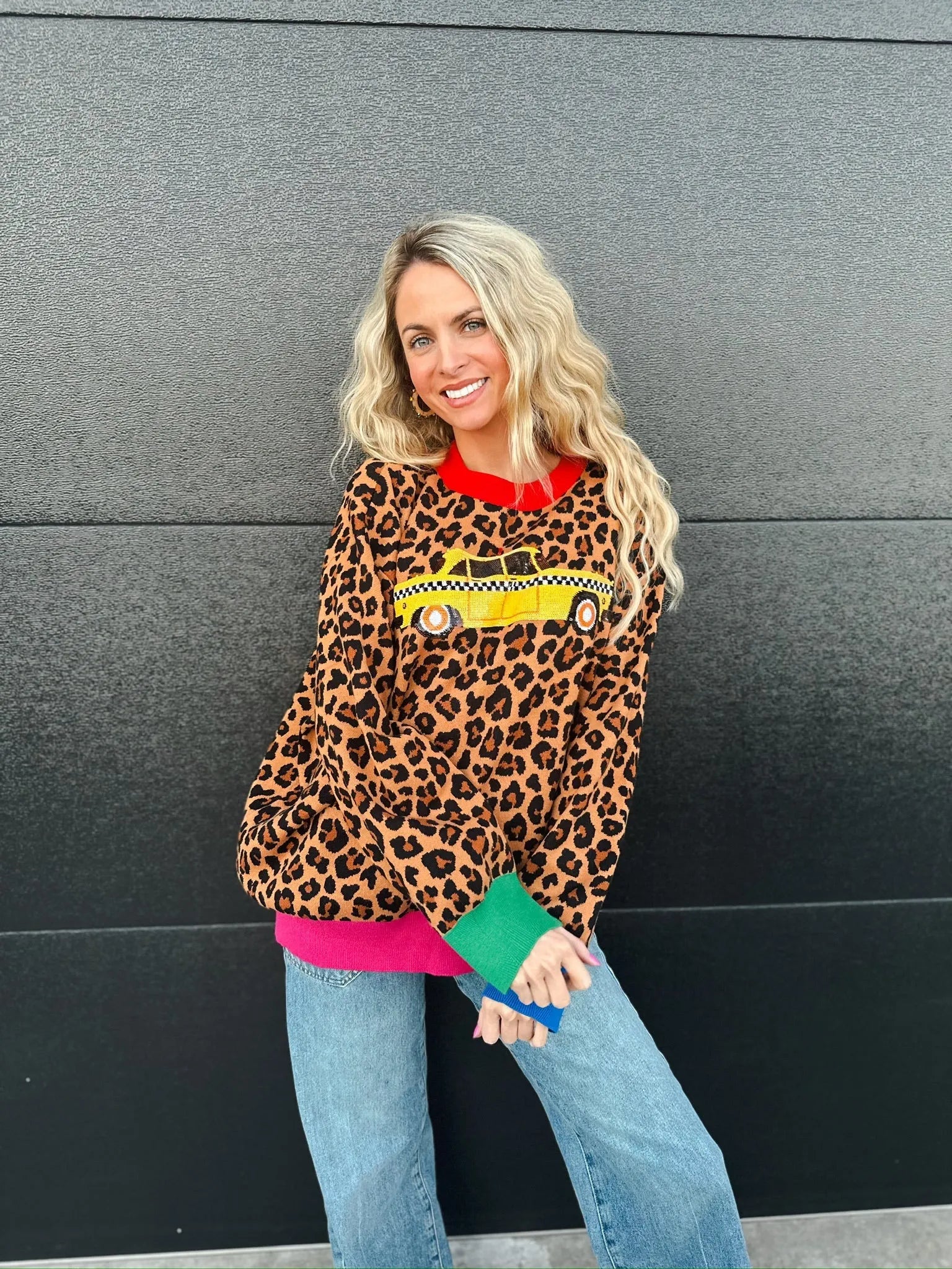 Queen of Sparkles leopard print sweater with a yellow taxi cab graphic, red collar, and colorful cuffs.