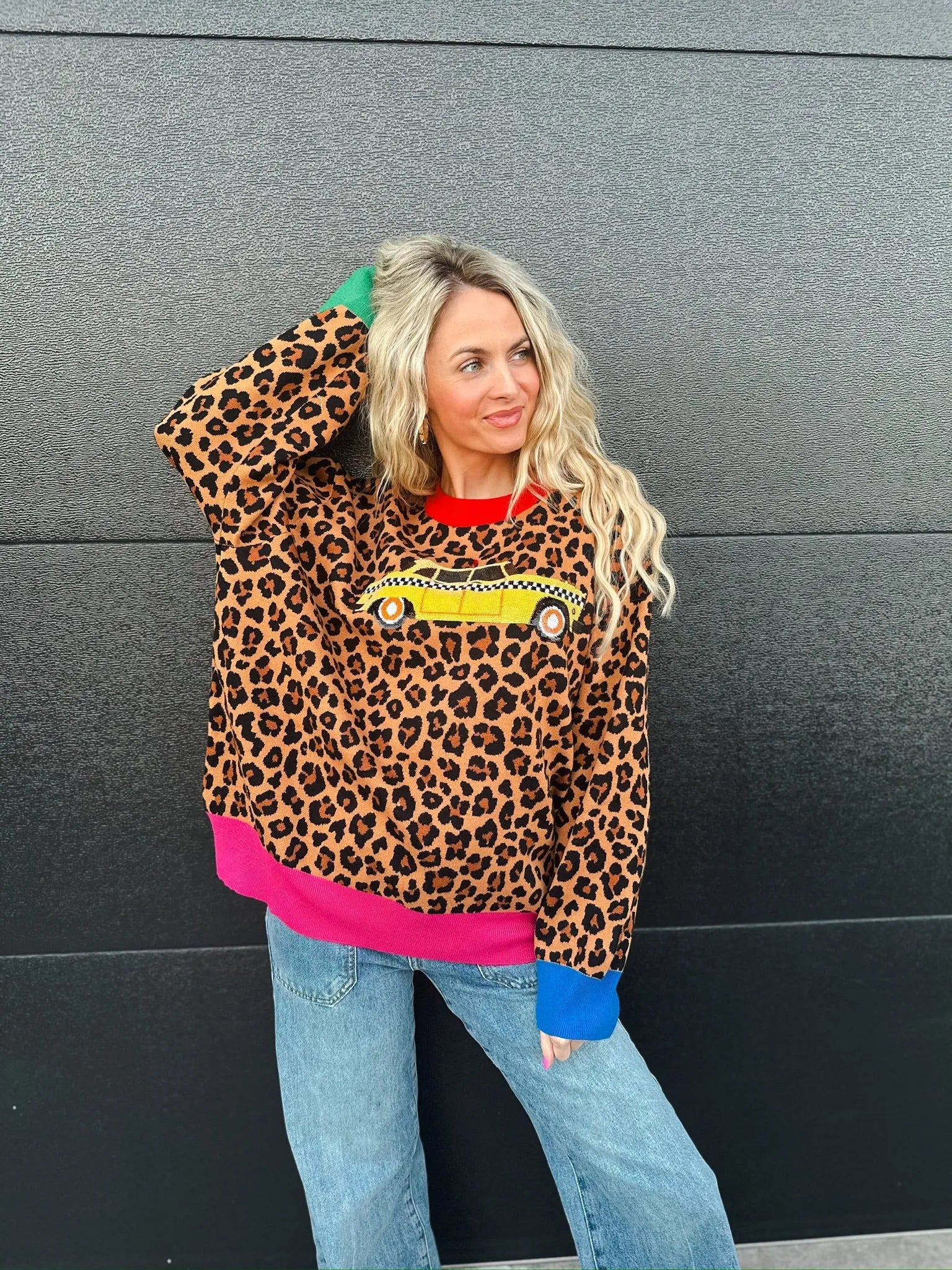 Queen of Sparkles leopard print sweater with yellow taxi cab graphic, red collar, pink hem, and blue cuffs.