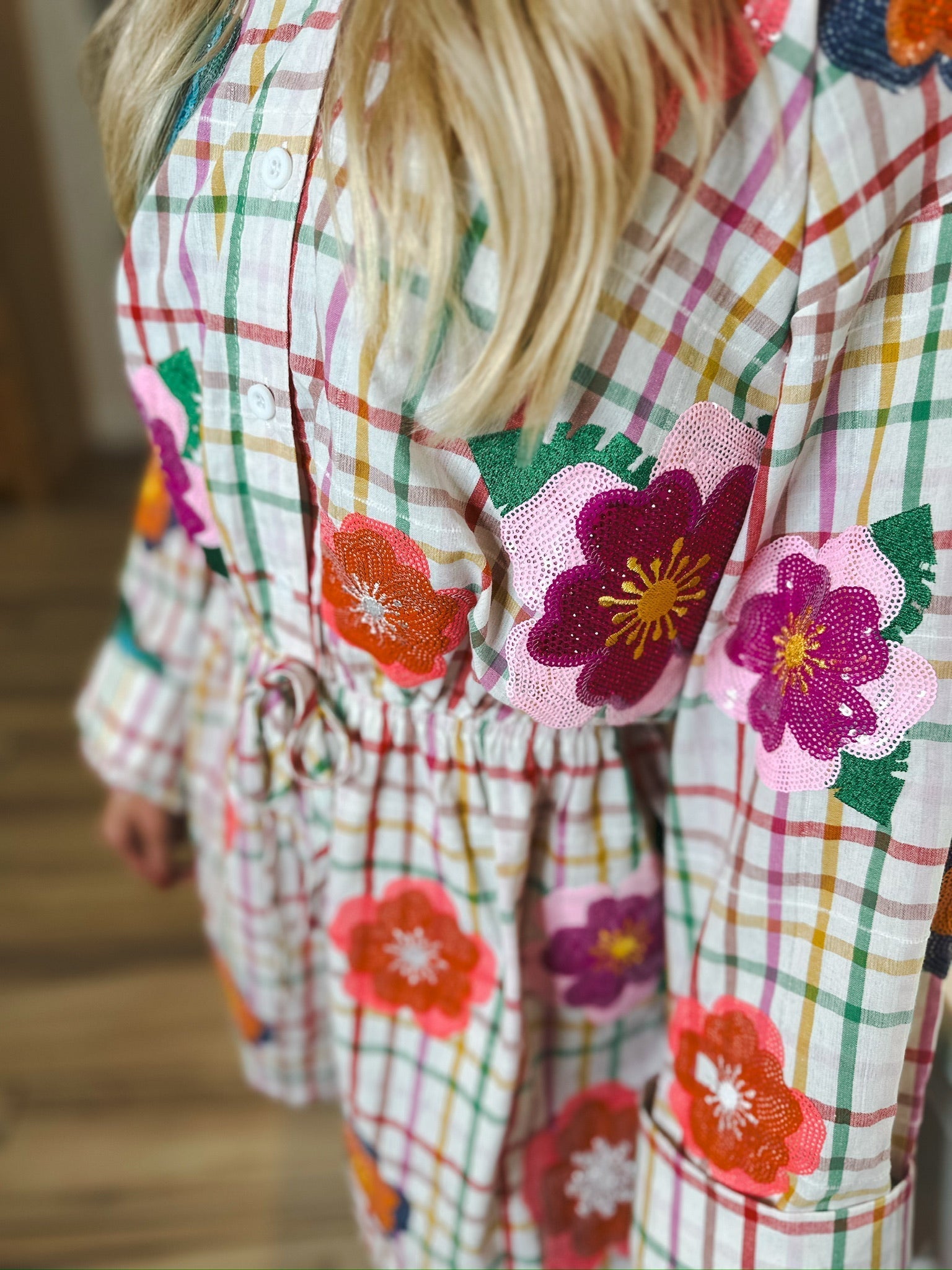 Queen of Sparkles rainbow plaid cotton romper with sequin floral appliques and a tie waist.