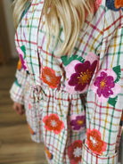 Queen of Sparkles rainbow plaid cotton romper with sequin floral appliques and a tie waist.