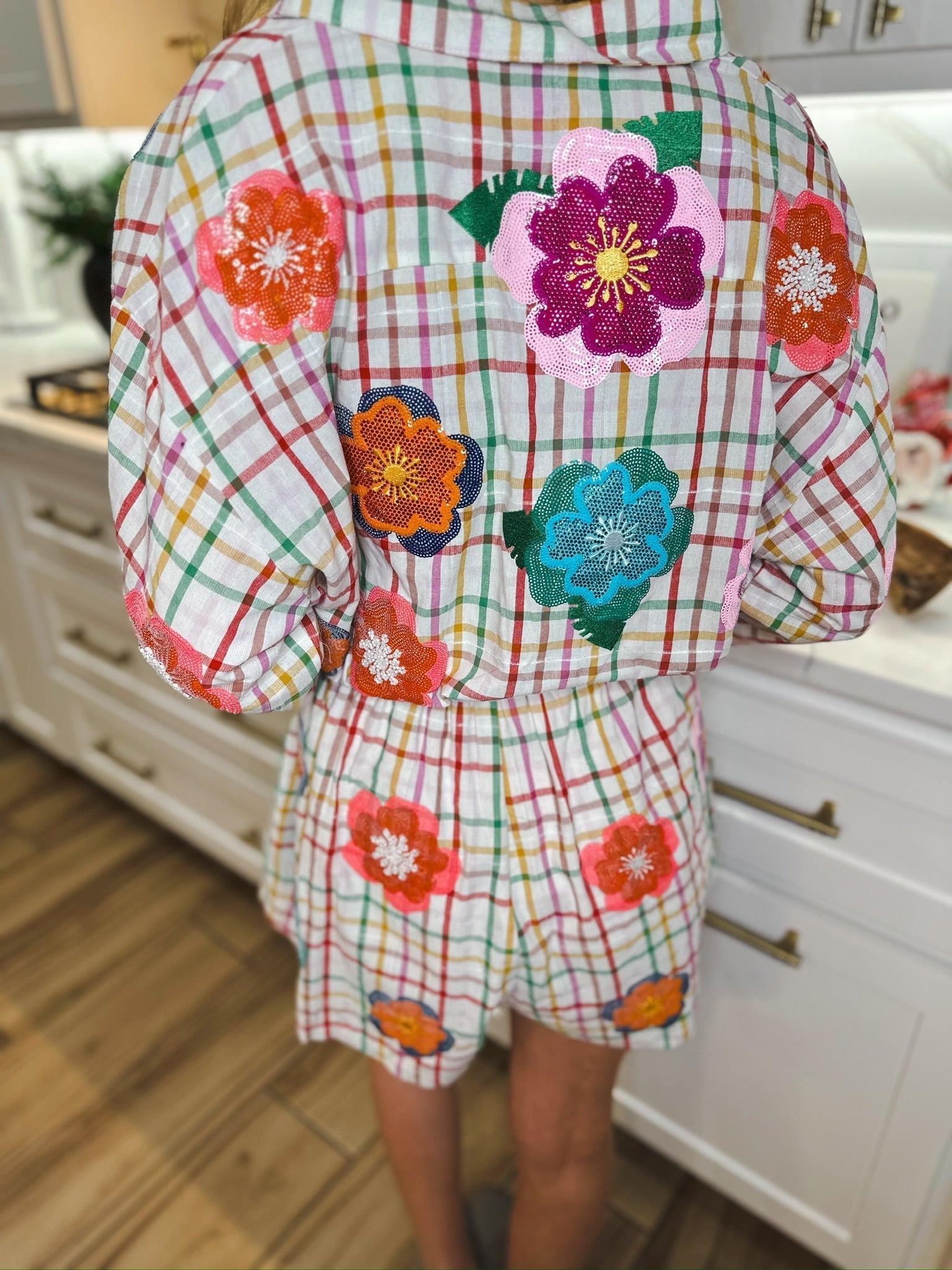 Queen of Sparkles rainbow plaid romper with colorful sequin flower appliques on sleeves and shorts.