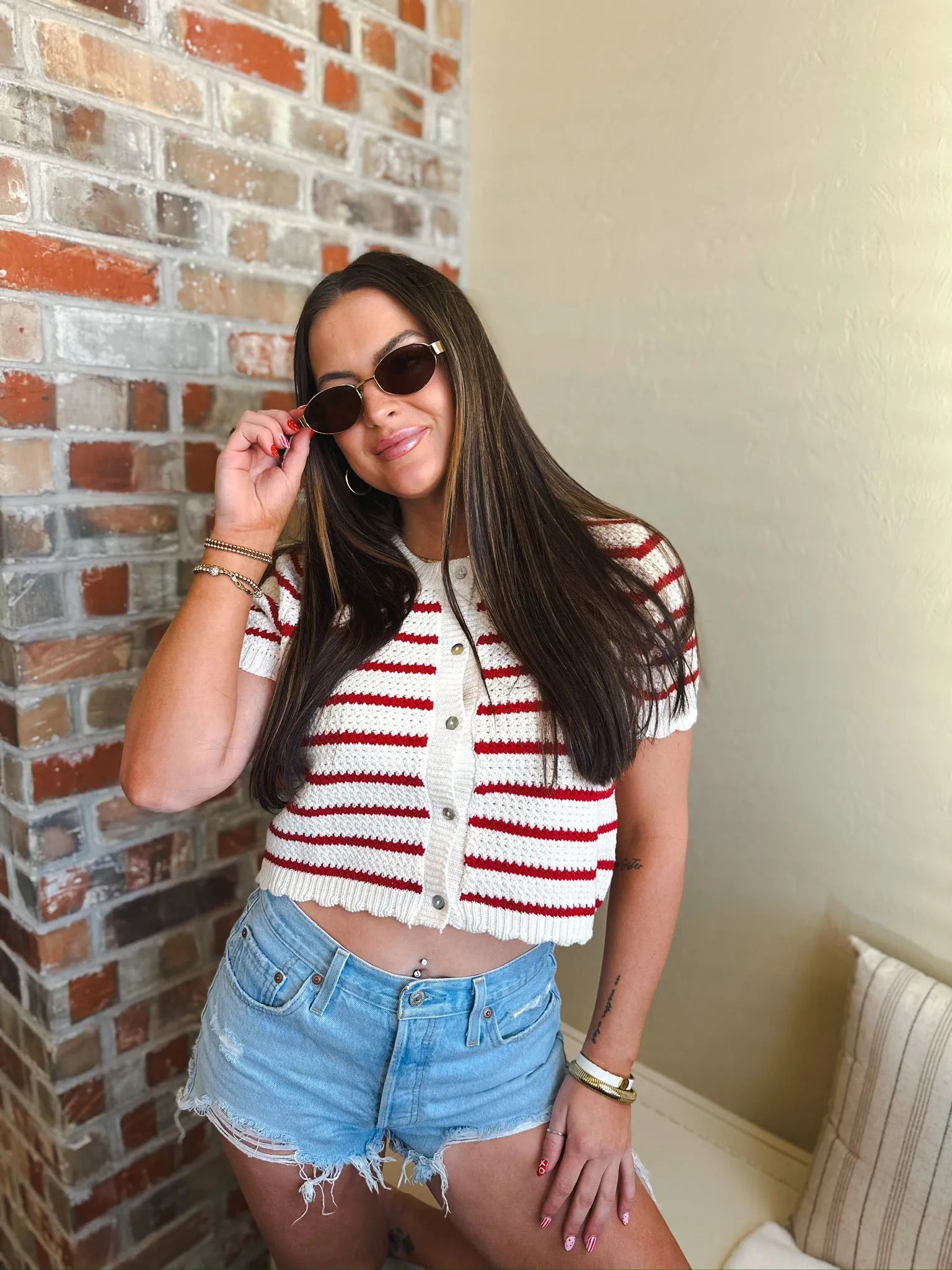 Cropped red and cream horizontal striped short sleeve button down cardigan sweater with white buttons.