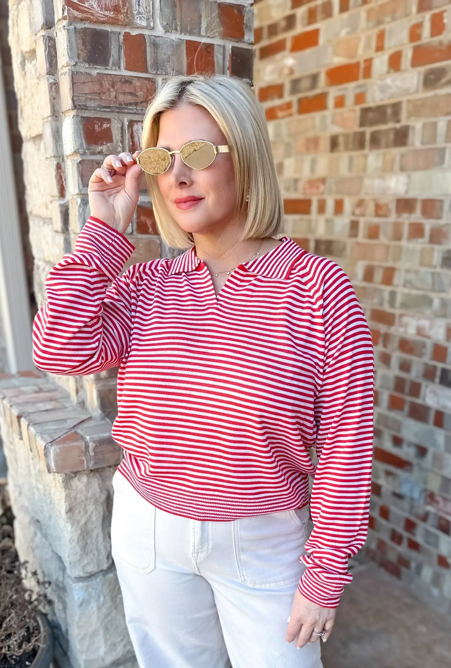 Red and cream striped collared pullover sweater top with a v-neck, worn by a woman with blonde hair and sunglasses.