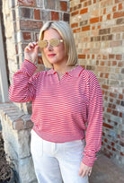 Red and cream striped collared pullover sweater top with a v-neck, worn by a woman with blonde hair and sunglasses.