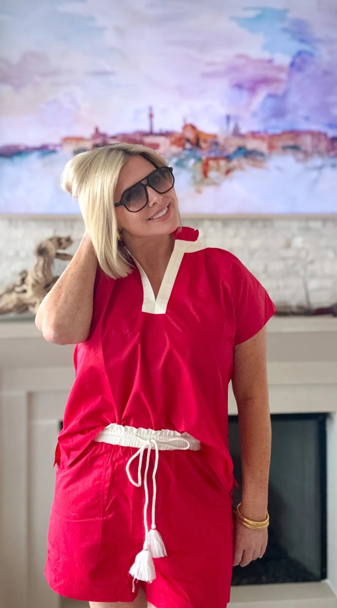 Woman wearing Entro red short set with cream trim, white drawstring shorts with tassels, and sunglasses.