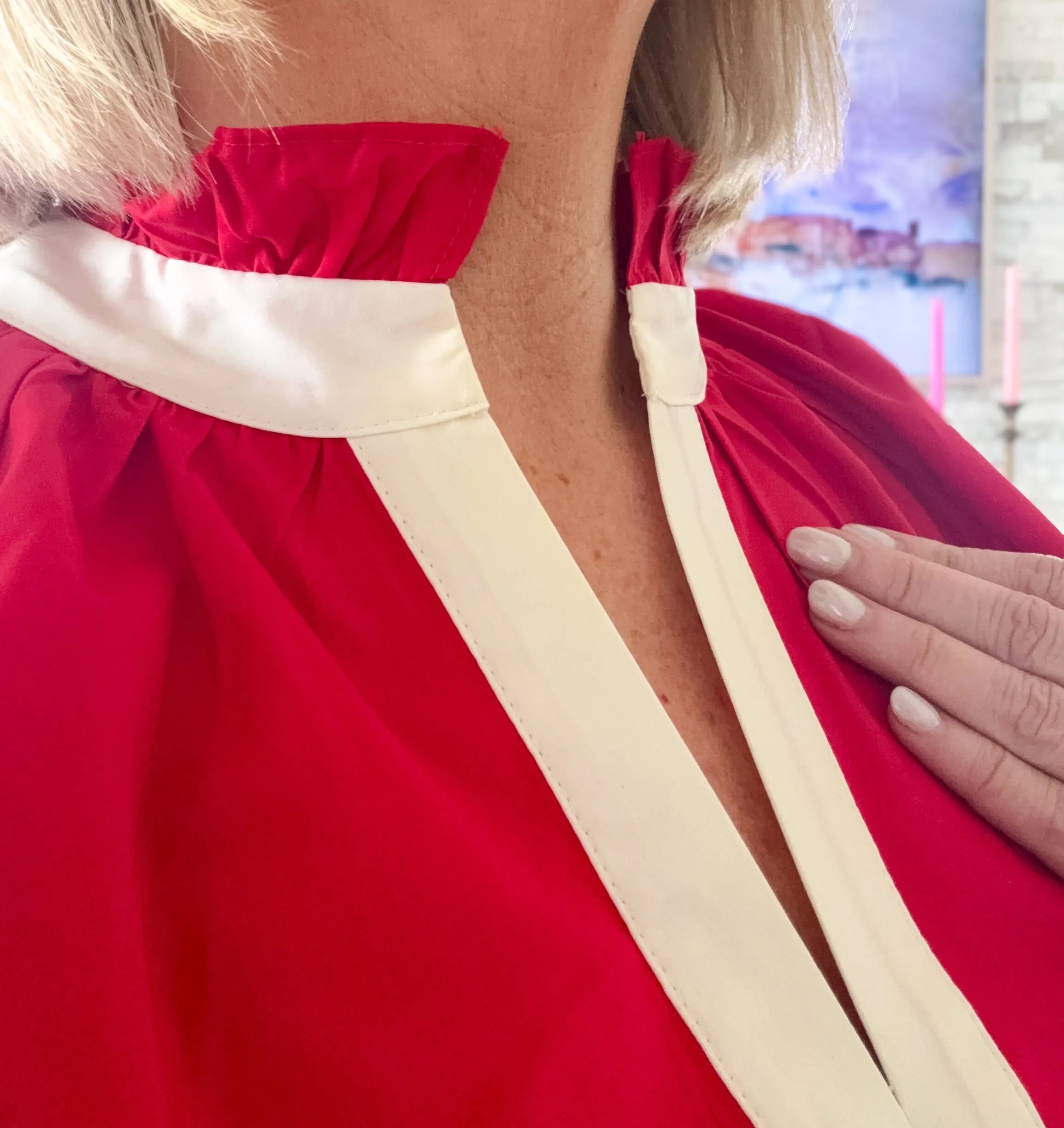 Entro red short set with cream trim and ruffled collar. Close-up showing neckline detail on a woman.
