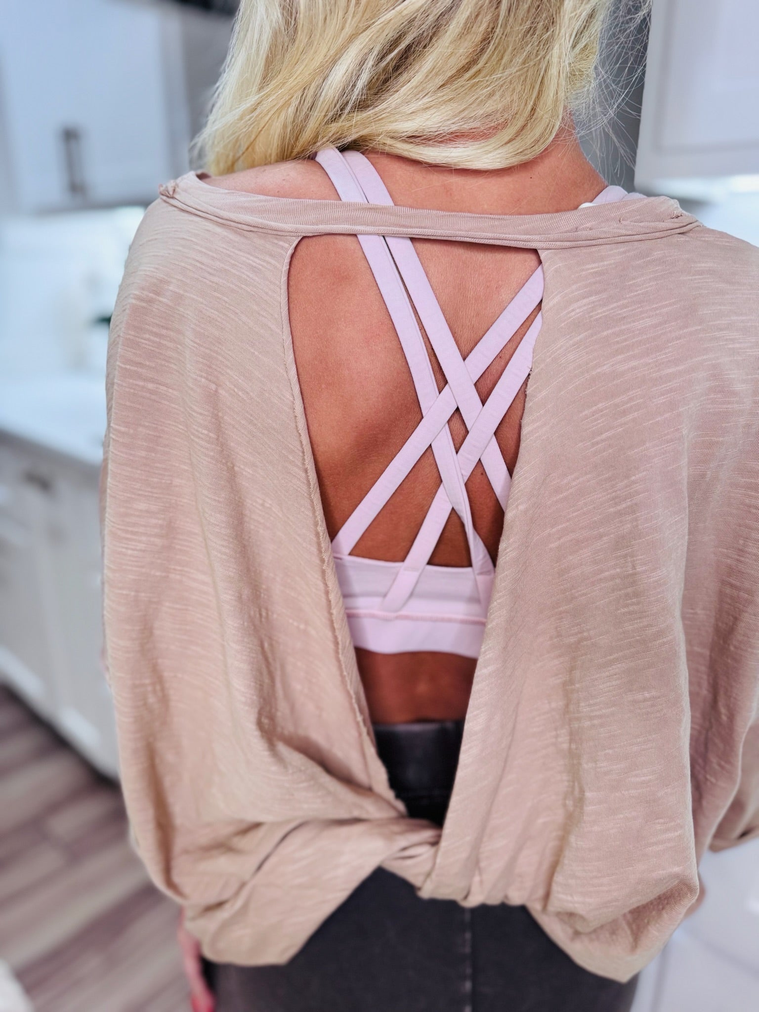 Taupe twist back cropped tee with pink strappy sports bra showing through the back cutout.