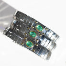 Three silver link chain bracelets, each featuring oval green emeralds set in gold bezels with gold accent beads.