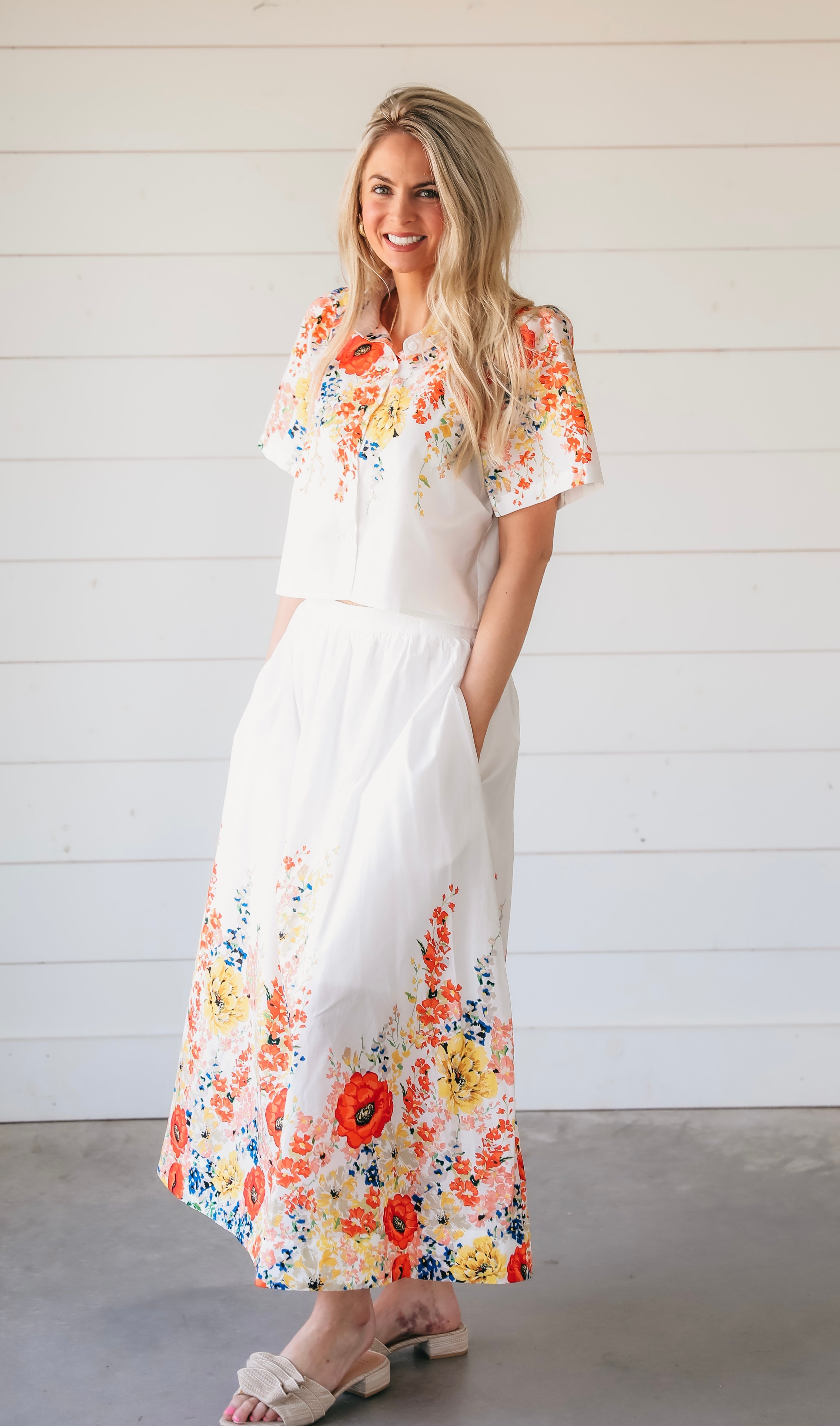 White floral two-piece maxi skirt set featuring a cropped short-sleeve top and a flowing skirt with vibrant red, yellow