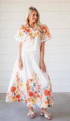 White floral two-piece maxi skirt set. Short-sleeve collared top and flowy maxi skirt with vibrant floral print of red